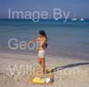 GW34960-60 = Young topless lady applying sun cream on Es Trenc beach( with boats at anchor behind ) in SE Mallorca / Majorca, Balearic Islands, Spain.  17th August 2009. Model Release.