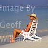 GW16260 = Scene on Es Trenc beach ( Platja de Trenc) in SE Mallorca ( girl in straw hat and bikini sitting on beach chair by waters edge ), Baleares, Spain. 21st September 2003. Model Release. 